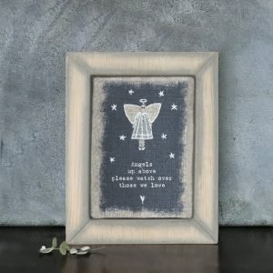 A small framed picture with an image of an angel and the words Angels Up Above Please look after those we love embroidered on it.