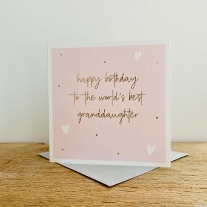 A square Pink card with gold dots and white hearts and the words Happy Birthday to the Worlds Best Granddaughter in gold print