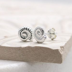 A pair of sterling silver stud earrings that are shaped like a fossil shell.