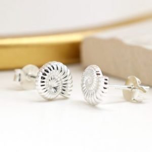 A pair of sterling silver stud earrings that are shaped like a fossil shell.