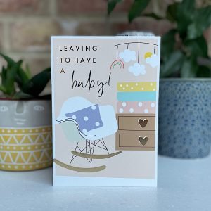 A card with an image of a babies nursery with a rocking chair and the words Leaving to have a babu printed on it.