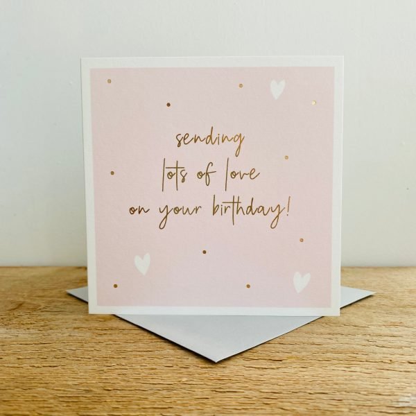 A square Pink card with gold dots and white hearts and the words Sending Lots of Love on Your Birthday in gold print