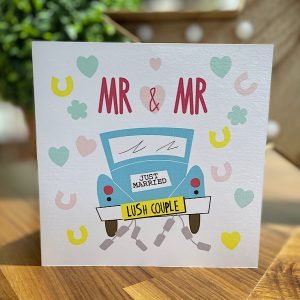 A wedding card with an image of the back of a wedding car with Lush Couple number plate and Mr and Mr printed about in burgundy on a background of confetti and horseshoes