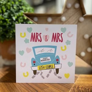 A wedding card with an image of the back of a wedding car with Lush Couple number plate and Mrs and Mrs printed about in burgundy on a background of confetti and horseshoes