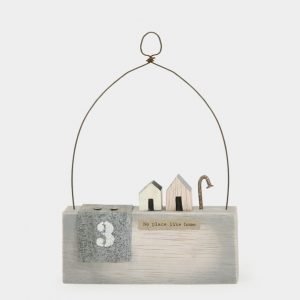 A sweet wooden keepsake with little wooden houses a wire arch over it and the words No Place Like Home printed on it