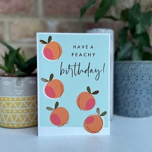 A card with a pale blue background and images of little peaches on it and the words Have Peachy Birthday printed on it.