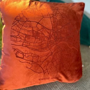 A fabulous rust coloured velvet cushion with a map of Newcastle and Gateshead imprinted on it.