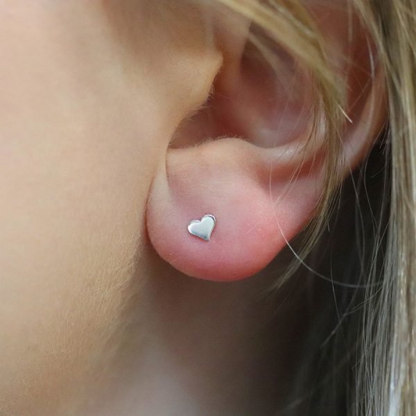 A pair of tiny sterlind silver heart stud earrings.