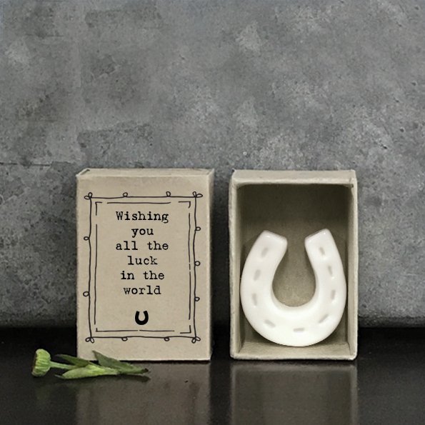 A small porcelain horse shoe keepsake in a matchbox with the words Wishing you all the luck in the world printed on it.