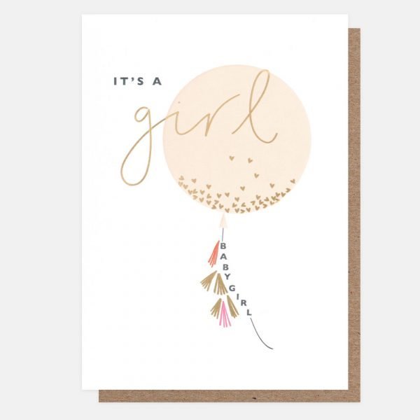 A new baby card with an image of a pale pink balloon with gold hearts printed on a white background. The balloon has gold foil and pink tassels and has "baby girl" incorporated into the string. "It's a girl" is printed across the balloon with "girl" being in gold foil