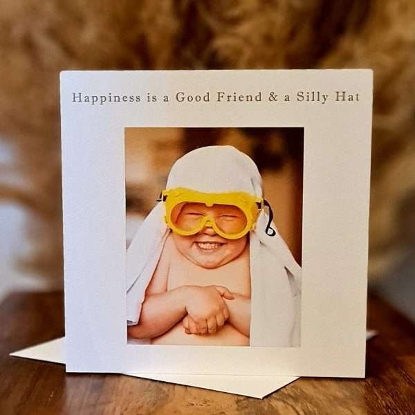 Good Friends and Silly Hats Birthday Card. A card with a photograph of a little boy giggling wearing a pair of yellow goggles and a towel on his head. The caption reads " Happiness is a Good Friend and a Silly Hat"