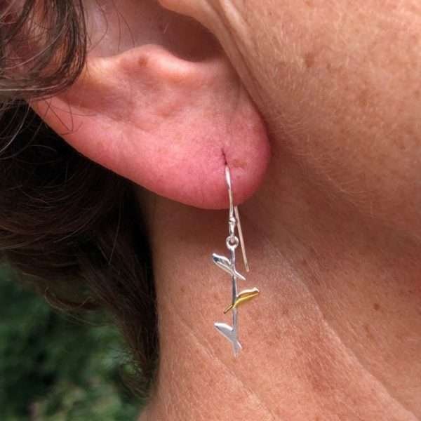 A stunning pair of sterling silver earrings with a long stick with three little birds on them. The middle bird is gold plated.