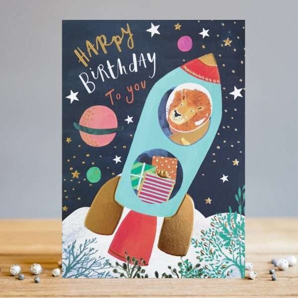 A lovely card from designer Louise Tiler with an image of a rocket on the moon with a lion sitting at one of the windows and presents in the other window. The words Happy Birthday are printed on the card.