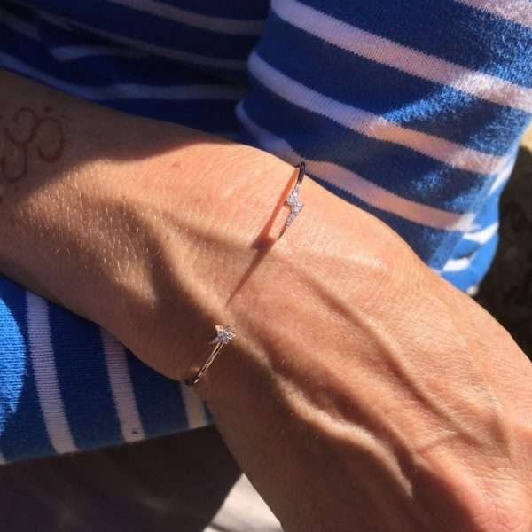 A sterling silver cuff bangle with a lightening bolt on one side of the bracelet and a star on the other side. Both lightening bolt and star are covered in tiny cubic zirconia.
