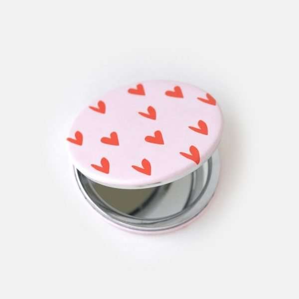 A round pocket mirror decorated with little red hearts