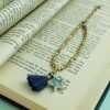 A gold bead bracelet with a denim blue enamel star pendant and a blue and gold tassel