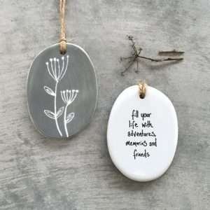 A gorgeous ceramic hanging keepsake with a lovely floral design on one side and the words Fill your life with adventures memories and friends on the other side.