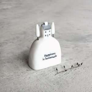 A sweet porcelain ornament with a hill design with sweet house and trees on it. The words Happiness is Handmade are written on the ornament.