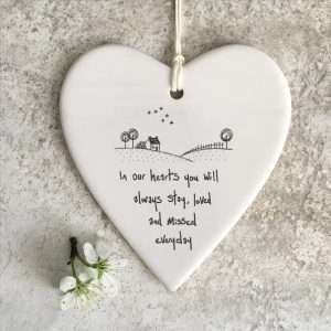 A lovely ceramic white hanging heart with the wording In OUr hearts you will stay, loved and missed every day.