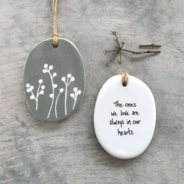 A gorgeous ceramic keepsake with a lovely floral design on one side of it and the words The ones we love are always in our hearts on the other side.