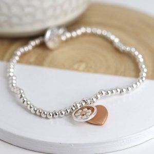 Stretch bracelet made from little round silver plated beads, with a mixed metallic daisy circle charm and rose gold style heart charm in a matt finish.