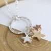 Triple Star Necklace. Silver plated split chain necklace with a hammered silver plated hoop pendant and three star charms of different sizes in contrasting silver, gold and rose gold style finishes. This necklace is fastened with a lobster clasp and has an extension chain to adjust the length.