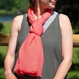 Coral Lightweight Crinkle Scarf. Lightweight scarf in coral pink with a fine pleated texture and lightly frayed ends.