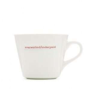 A plain white ceramic mug with the words Overworked/Underpaid printed on the front of it.