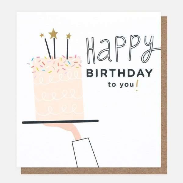 A contemporary birthday card with a cake being presented on a plate by a hand and an arm. The cake is pink and has candles with stars. Happy Birthday to you!