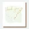 A thank you card with a pen writing in gold.The pen is white with gold hearts and thank you is written in gold