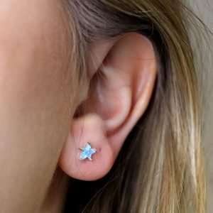 Sterling silver star stud earrings with deep cut synthetic blue star shapes in claw settings