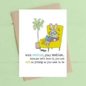 A birthday card with a bunny in an armchair with the words Work medium, play medium, because lets face it your aren't as young as you used to be