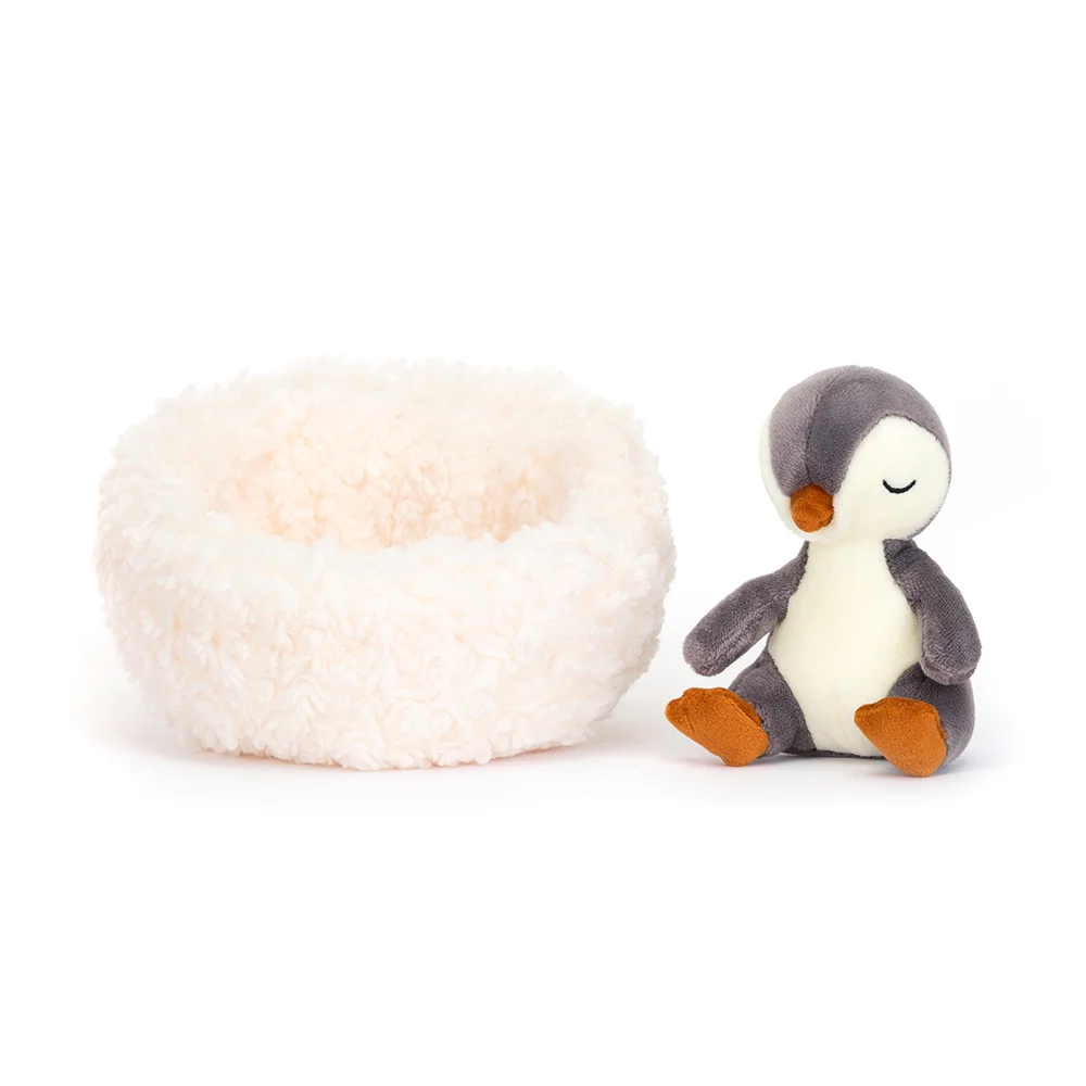 A little cuddly penguin in a white fluffy nest