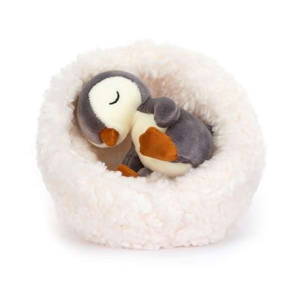 A little cuddly penguin in a white fluffy nest
