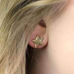 Star shaped stud earrings with faux gold plating in a worn finish and an off-centre single heart shaped white quartz set into each heart