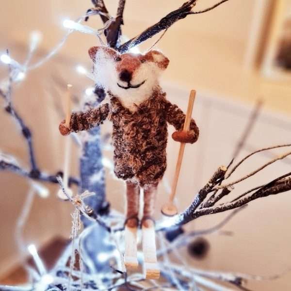 A felt fox in a wool coat. The fox is skiing and is a hanging Christmas decoration
