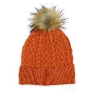 An burnt orange fleece lined, cable knit bobble hat in wool mix with a natural fuax fur pom pom