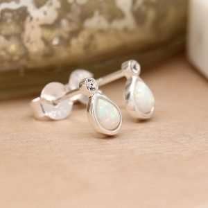 Sterling silver teardrop shaped stud earrings with white synthetic opals, each topped with a tiny clear crystal and fastened with sterling silver butterfly clasps