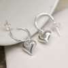 Sterling silver half hoop stud earrings with a puff heart charm on each
