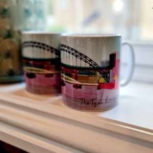 A procelain mug decorated with a colourful drawing of the Tyne Bridge
