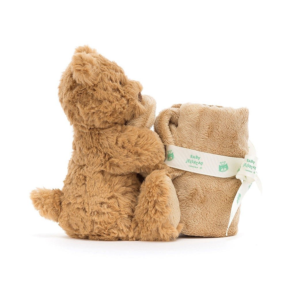 A brown softly textured toy bear is hugging an un-stuffed square shaped soother blanket