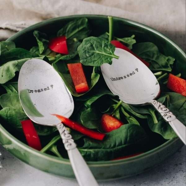 A pair of vintage serving spoons hand stamped with DRESSED on one spoon and UNDRESSED on the other