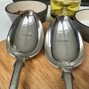 A pair of vintage serving spoons hand stamped with SALAD on one spoon and TOSSER on the other
