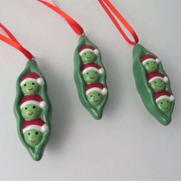 Three peas in christmas hats in a pea pod