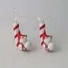 A ceramic candy cane wwith a little gonk sitting on hanging decoration