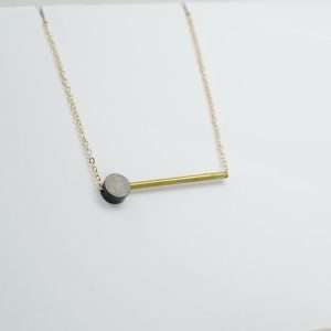 Bat and dot necklace. A black powder coated brass disc and a brass bar threaded onto a fine gold plated necklace