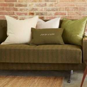 An oblong cushion in dark olive felt embroidered with you can never have too many cushions