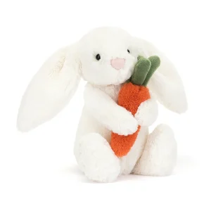 A soft toy from Jellycat a white fluffy bunny with a cute face holding a carrot