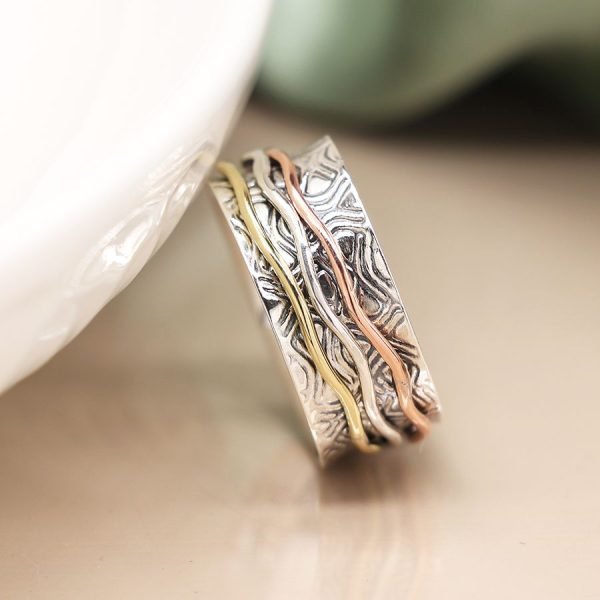 Sterling silver spinning ring with embossed pattern and three moving wave bands in silver, brass and copper