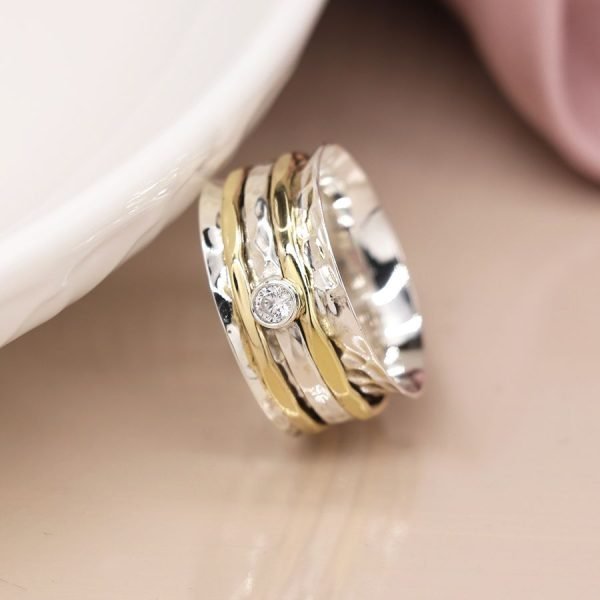 Sterling silver spinning ring with hammered surface and triple moving bands, one silver with a cut gemstone and two brass